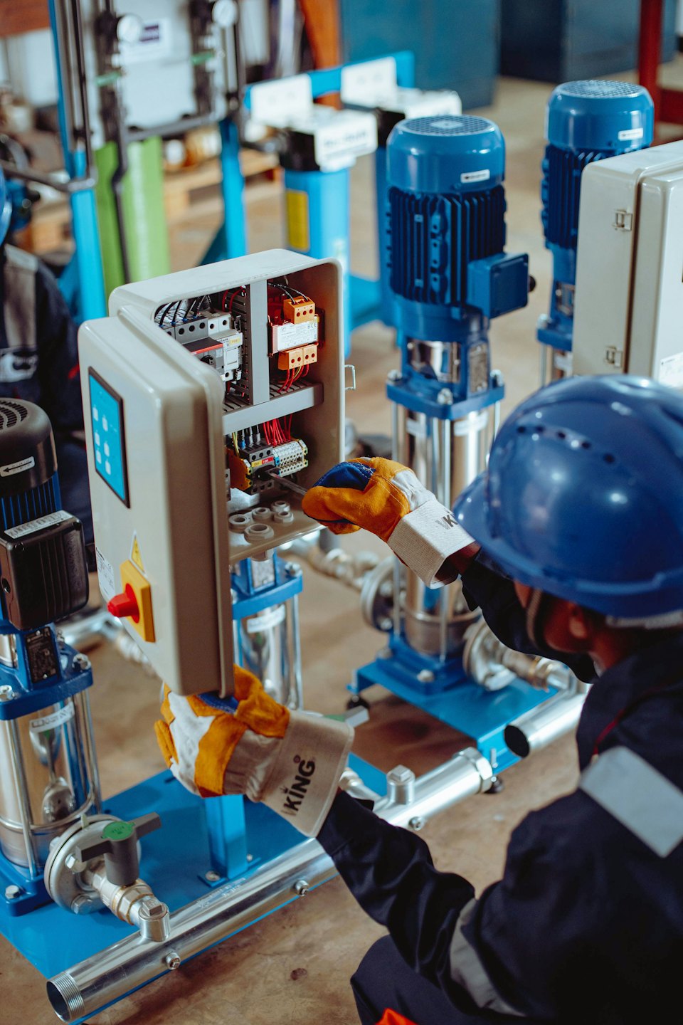 Teknisyen, kabloları olan açık bir elektrik kontrol paneli üzerinde çalışıyor.